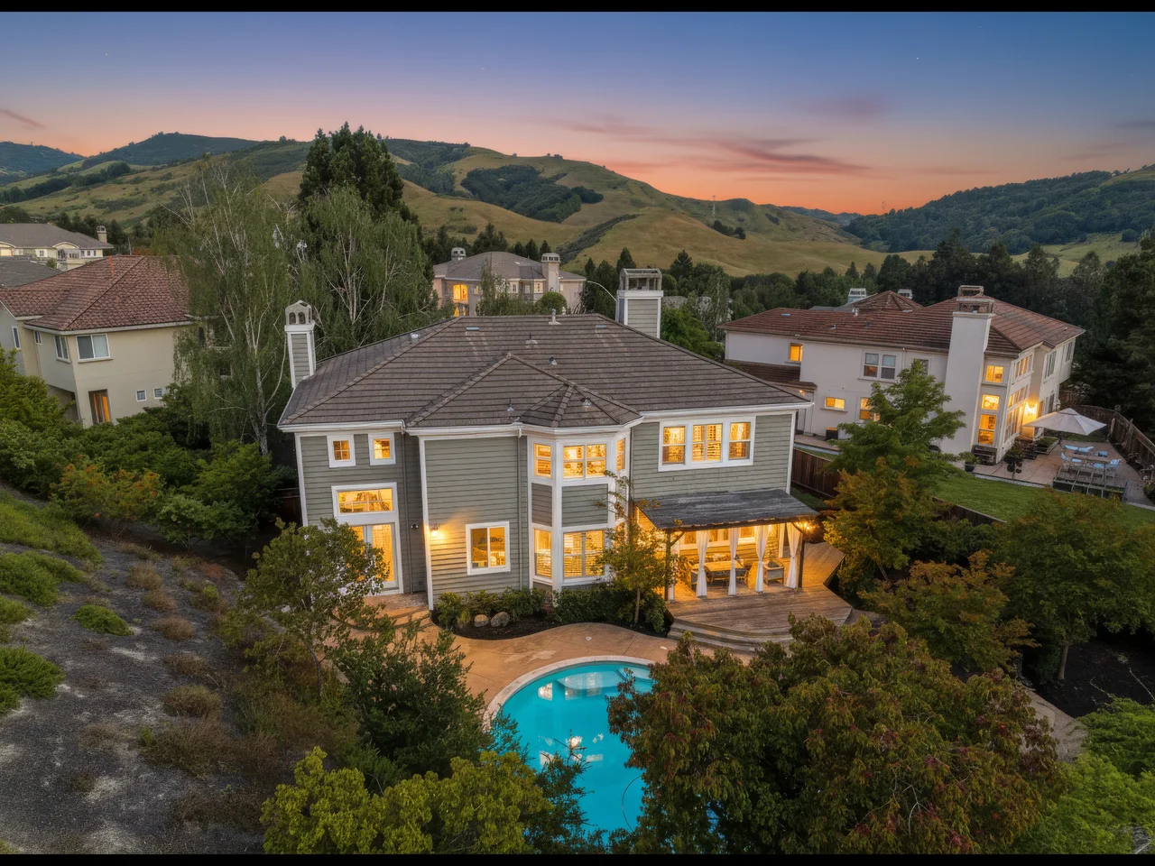 Aerial view of a hillside home and swimming pool at sunset