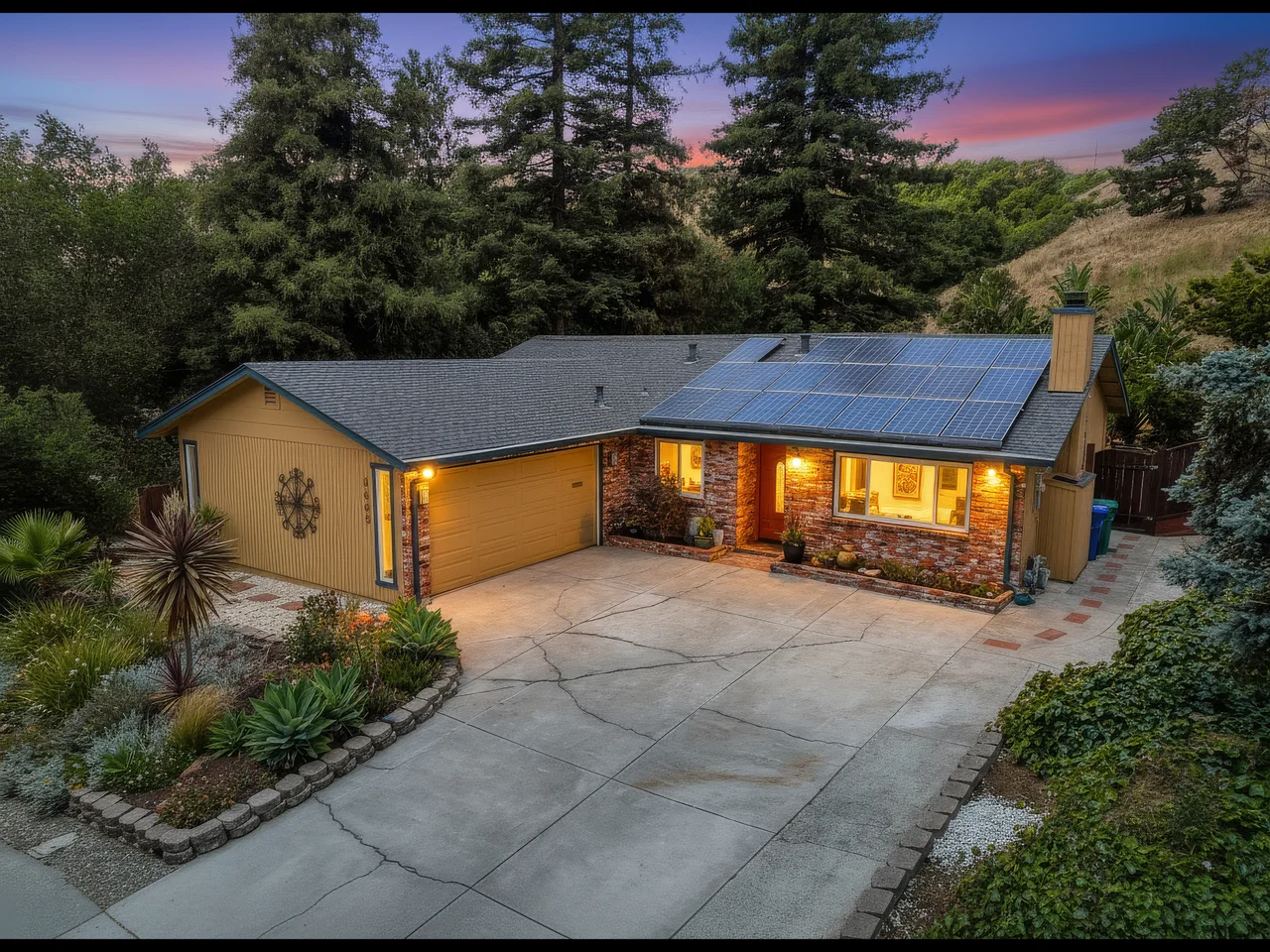 Elevated view of a single-story home framed by tall trees at dusk