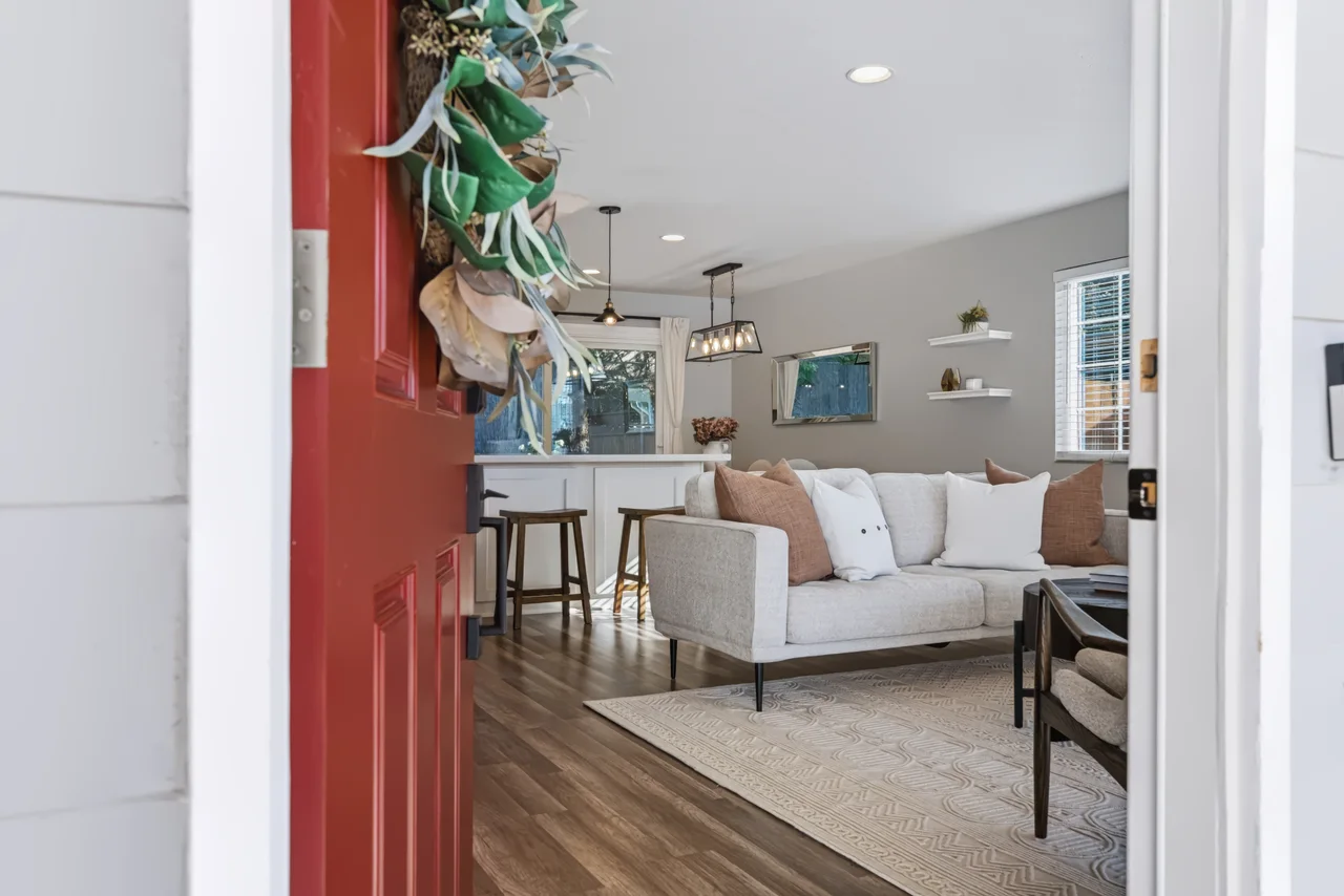 View through a red front door into an open living and dining space