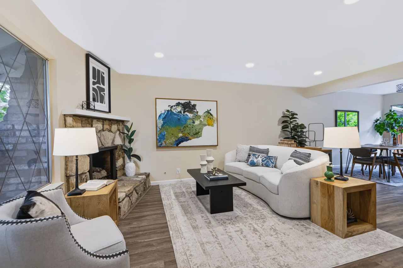 Living room with white seating, fireplace, and warm wood furniture
