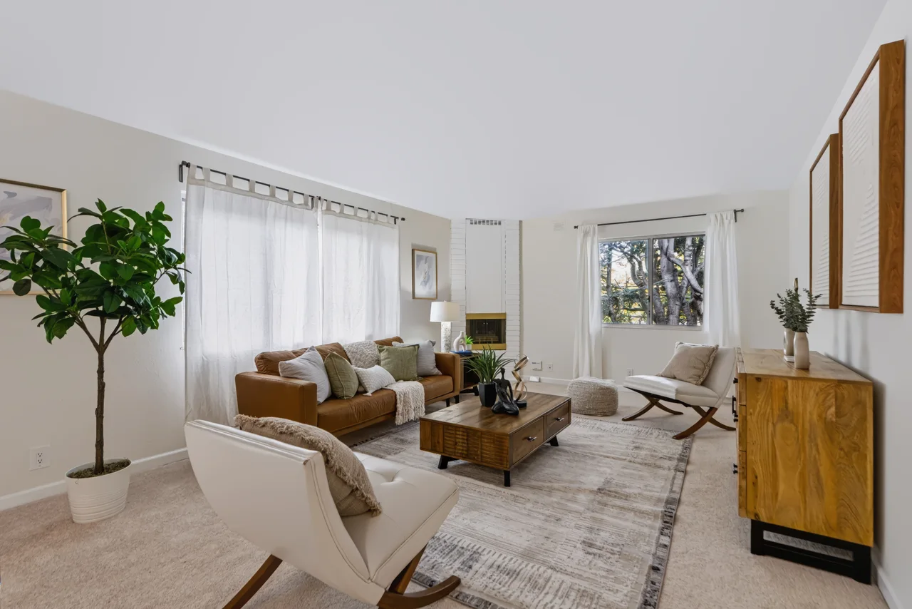 Neutral living room with a sofa, armchair, and wood console beside the stairs
