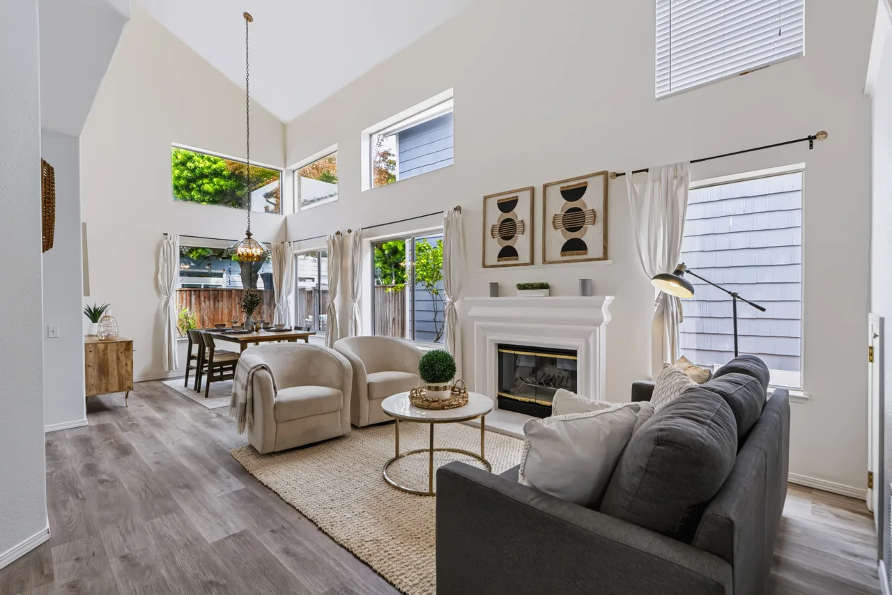 Double-height living room with high windows, a white fireplace, and garden doors