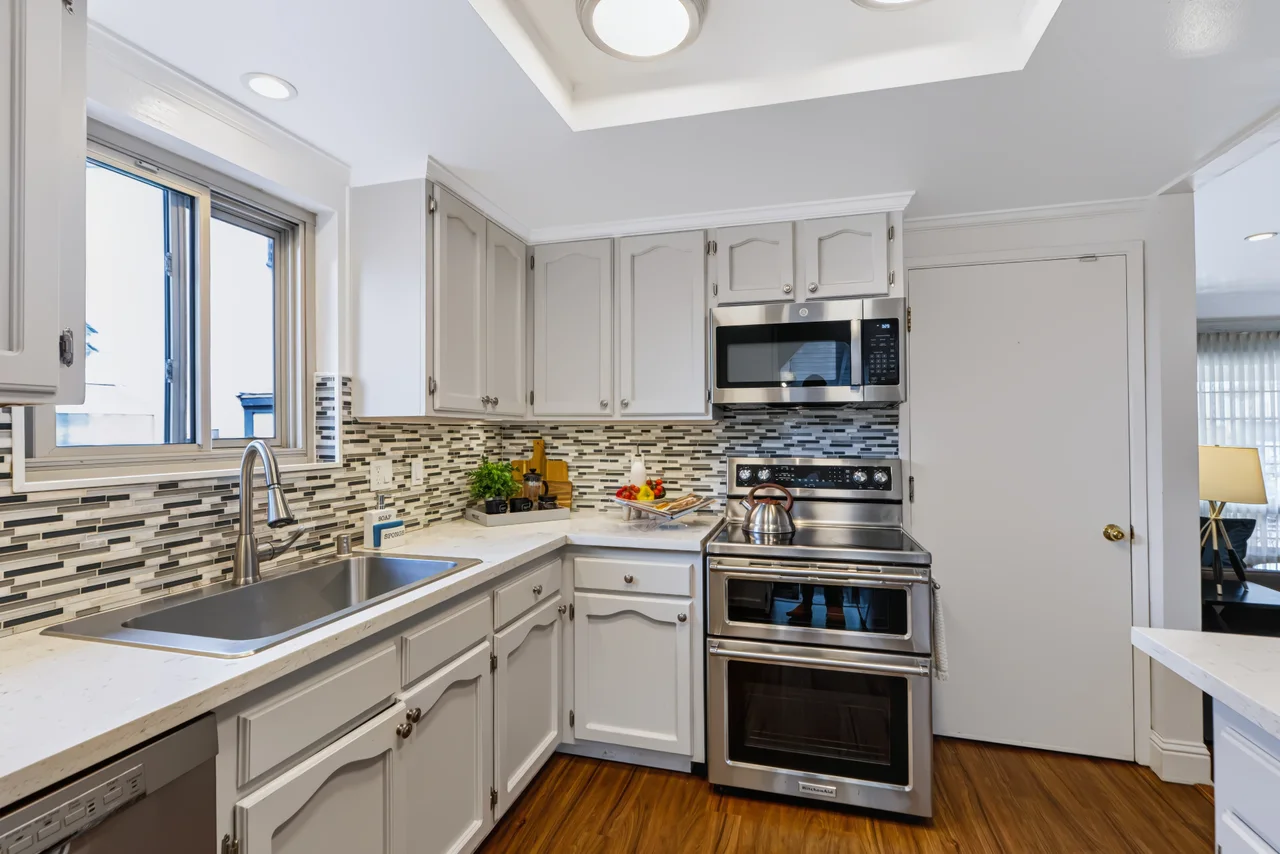 White kitchen with stainless steel appliances and a mosaic tile backsplash