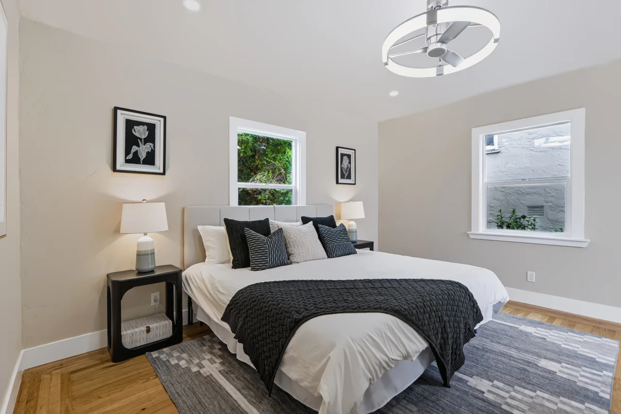 Bedroom with a dark upholstered bed, blue rug, and circular ceiling light