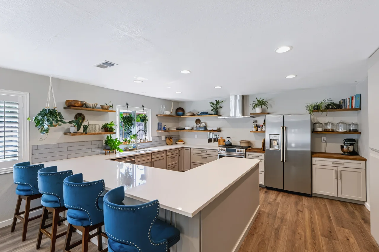 Open kitchen with a white island, blue bar stools, and stainless steel appliances