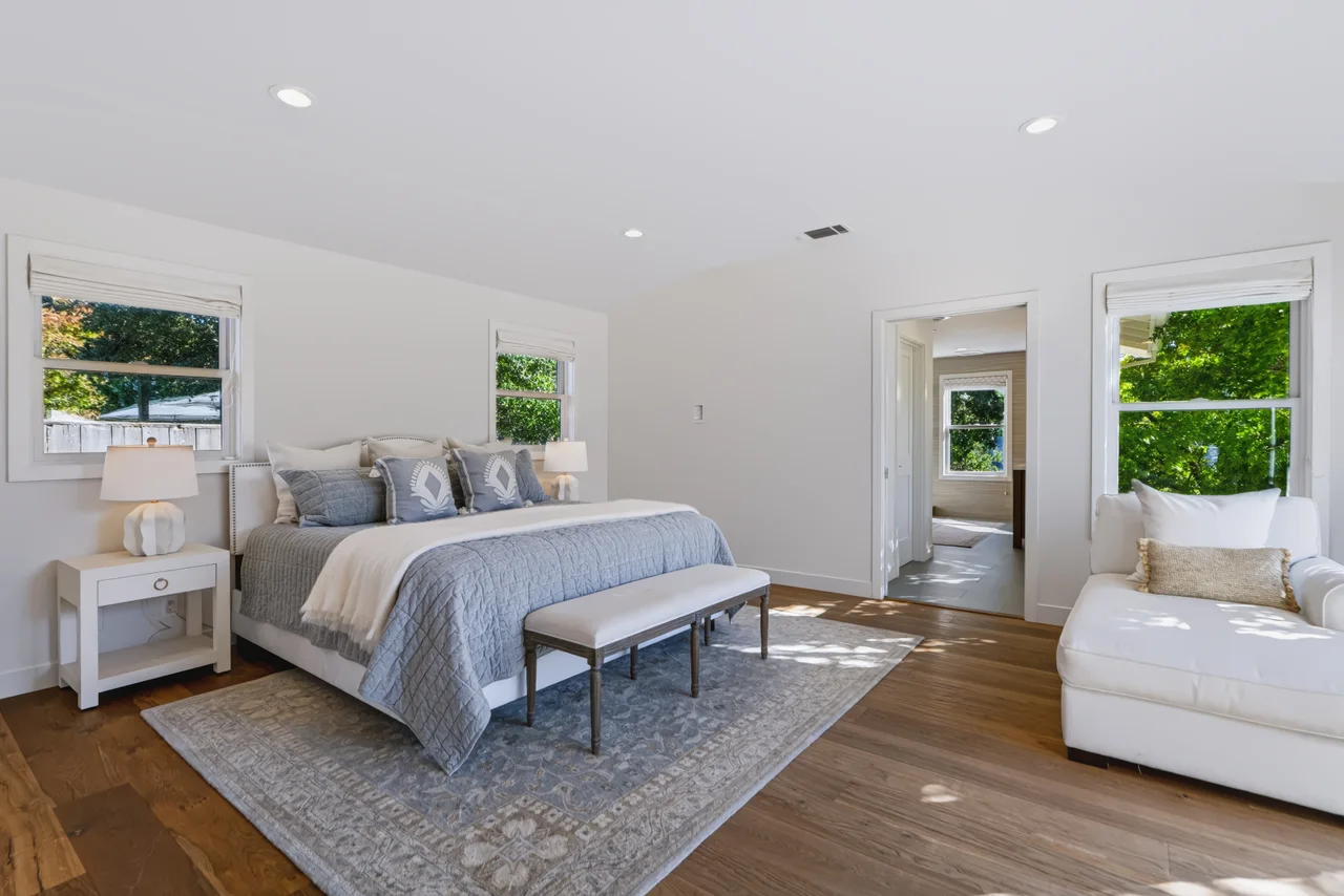 Spacious bedroom with a pale blue bed, white furniture, and garden doors