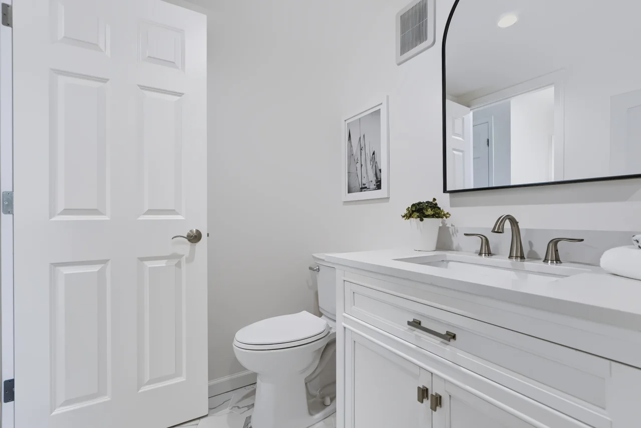 White bathroom vanity with framed artwork and a large mirror